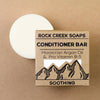 Rock Creek Soaps conditioner bar with packaging on a brown background
