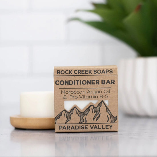 Rock Creek Soaps conditioner bar packaging on a surface with a blurred background