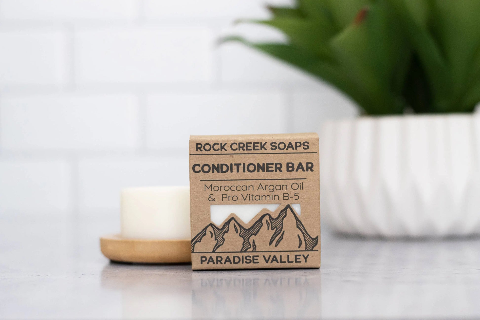 Rock Creek Soaps conditioner bar packaging on a surface with a blurred background
