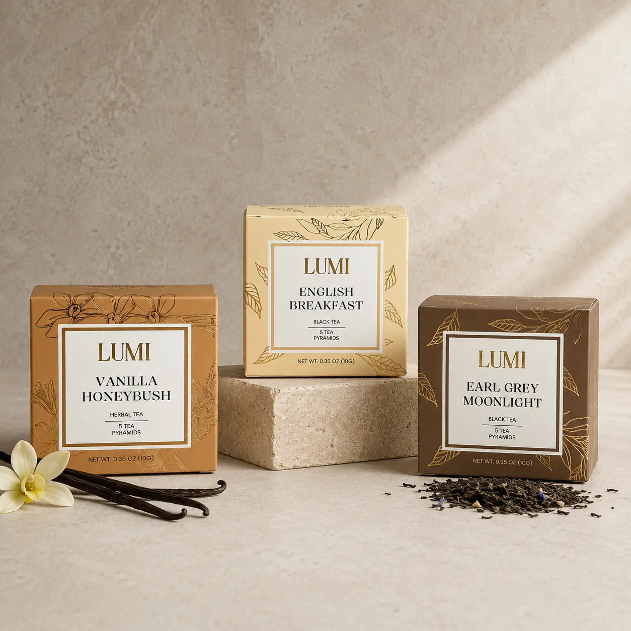 Three LUMI tea packages on a neutral background with vanilla beans and a flower.