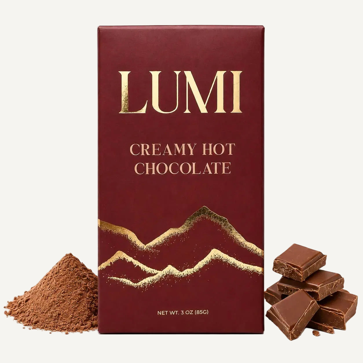 A 3 oz box of LUMI Creamy Hot Chocolate in its burgundy and gold wrapper, displayed with a pile of cocoa powder on the left and several broken chocolate pieces on the right, all on a clean white background.
