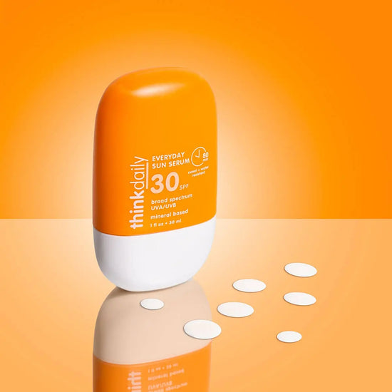 Orange and white bottle of think daily Everyday Sun Serum SPF 30 on an orange background
