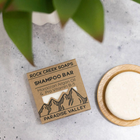 Rock Creek Soaps shampoo bar with packaging on a concrete surface