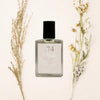 Perfume bottle labeled 'No. 74' with dried flowers on a light background