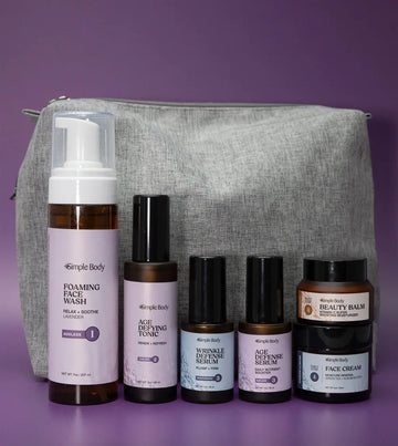 An Age Supporting Skincare Kit including a Foaming Face Wash, Age Defying Tonic, Wrinkle Defense Serum, Age Defense Serum, Beauty Balm, and Face Cream with a gray cosmetic bag on a purple background+
