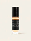 A clear glass bottle of Black Amber Perfume Oil with a black cap and black label, showing the amber-colored oil inside, set against a solid off-white background.