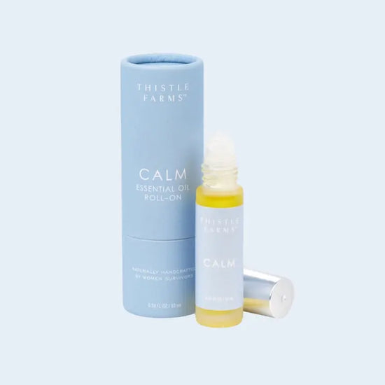 Thistle Farms Calm essential oil roll-on bottle and packaging on a light blue background
