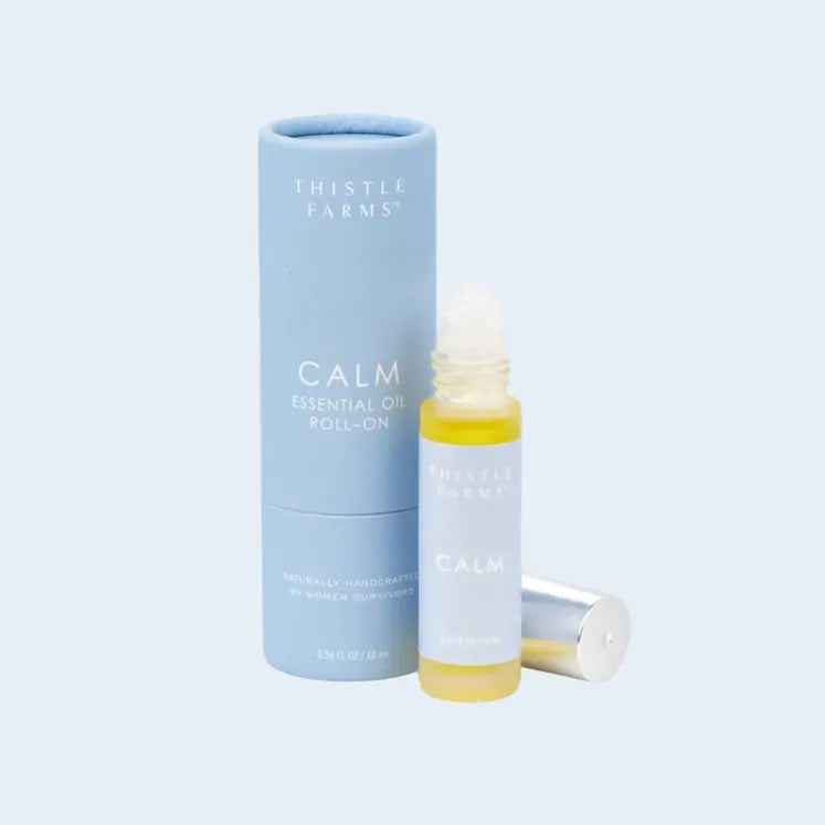 Thistle Farms Calm essential oil roll-on bottle and packaging on a light blue background