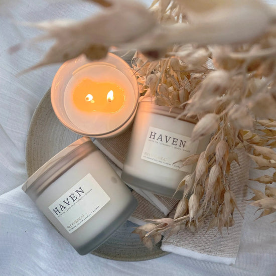 Three candles labeled "HAVEN" by Riley + Wheat showing it burning cleanly surrounded by wheat texture and sitting on a soft white linen texture.