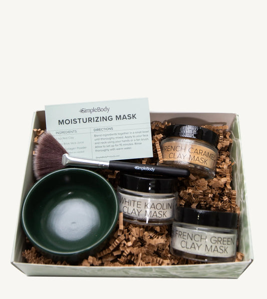 A photo of a Simple Body triple clay mask gift set including French Caramel Clay, White Kaolin Clay and French Green Clay with a dark green bowl, fan brush and recipe card.