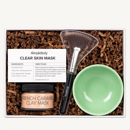 A clay mask gift set including a caramel clay mask, recipe card, green bowl and fan brush with kraft crinkle paper in a gift box.