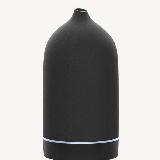 A modern ceramic essential oil diffuser in black against a white background.