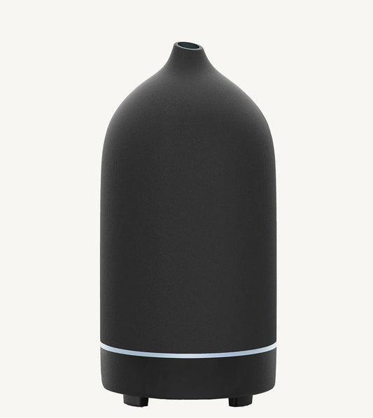 A modern ceramic essential oil diffuser in black against a white background.