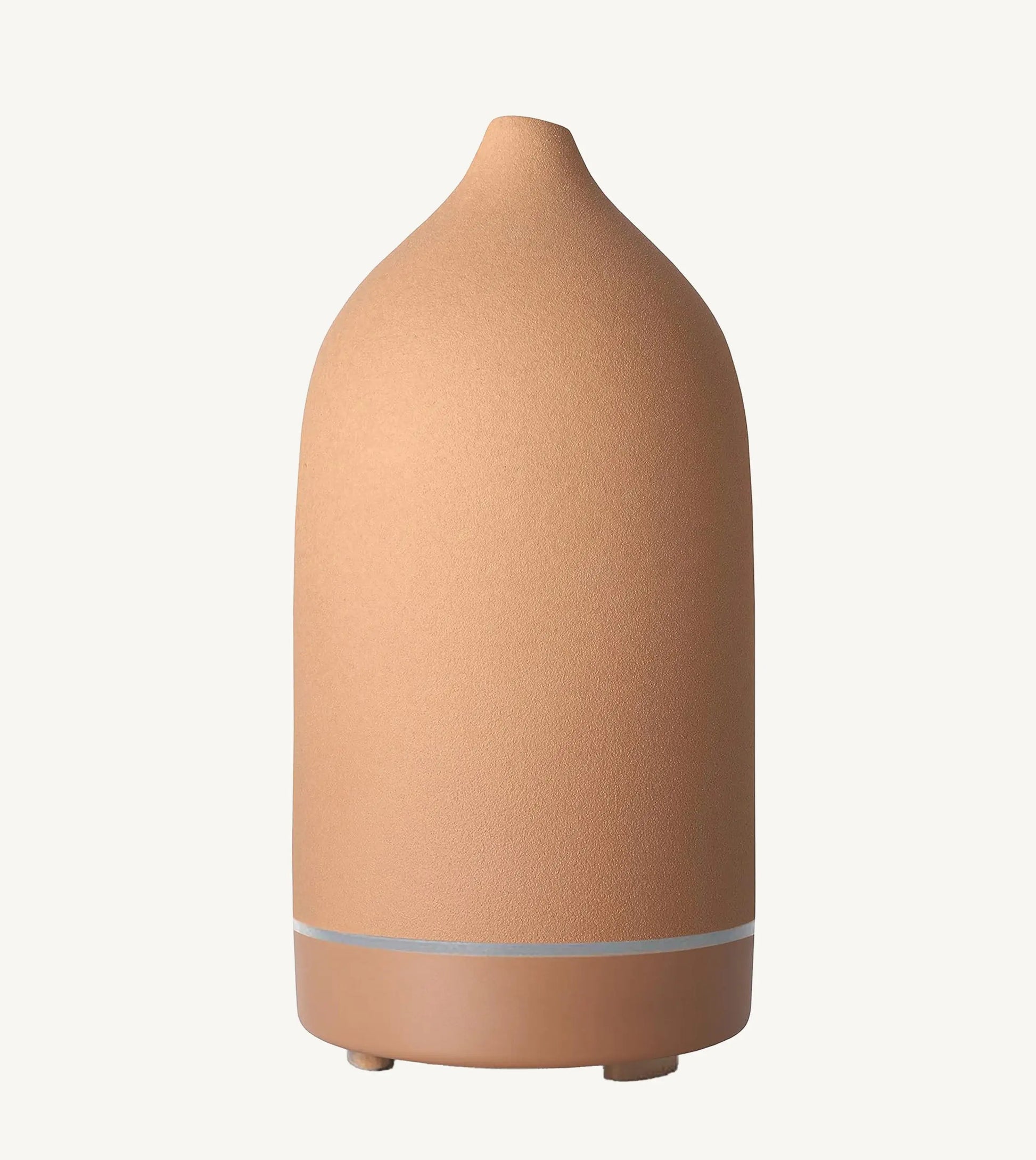 A modern ceramic essential oil diffuser in an earthy rust color against a white background.