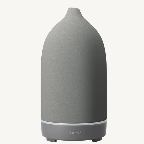 A modern ceramic essential oil diffuser in a medium gray color against a white background.
