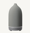 A modern ceramic essential oil diffuser in a medium gray color against a white background.