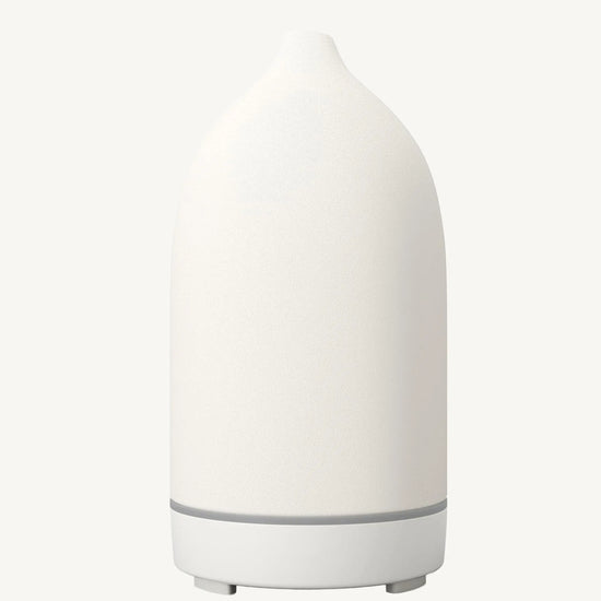 A modern ceramic essential oil diffuser in white against a white background.
