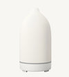 A modern ceramic essential oil diffuser in white against a white background.
