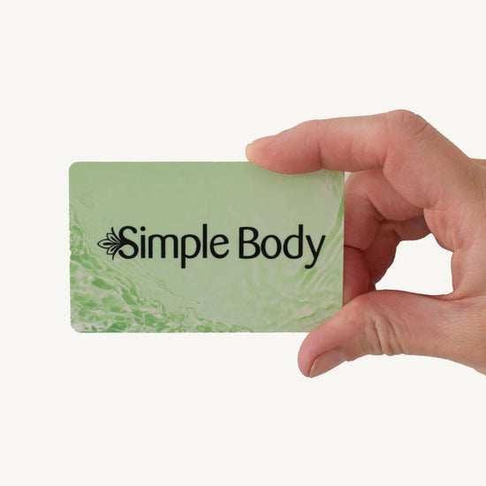 Hand holding a green gift card with 'Simple Body' logo against a white background