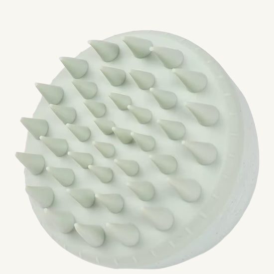 A photo of a mint green hair and scalp brush by Simple Body