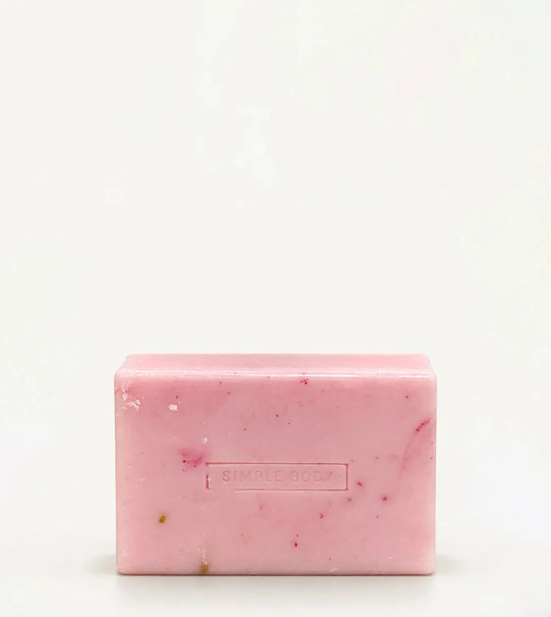 A handmade bar of soap with a pink color and an embossed Simple Body design on it, placed against a tan background.