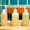Three bottles of Juniper Ridge body wash with different scents on a wooden surface.