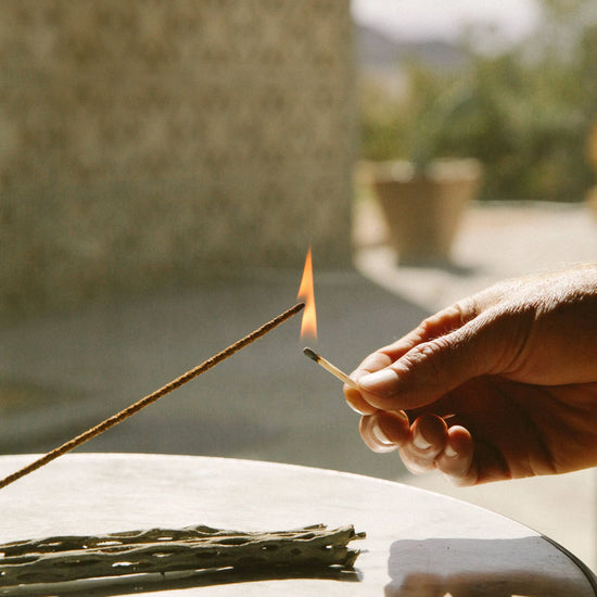 Person lighting a Juniper Ridge Campfire Incense stick in Cedar with a match outdoors