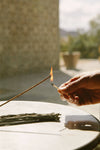 Person lighting a Juniper Ridge Campfire Incense stick in Cedar with a match outdoors