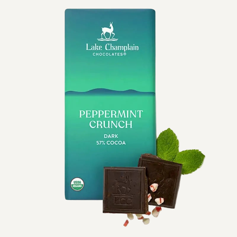 Lake Champlain Chocolates Peppermint Crunch dark chocolate bar packaging in a teal gradient box, shown with two broken chocolate squares and mint leaves on a white background.