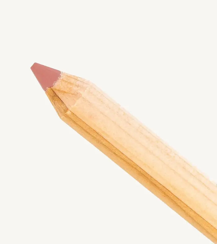 A closeup photo of Pure Anada's lip pencil stick with a warm pink flesh colored tip on a tan background.