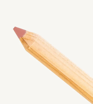 A closeup photo of Pure Anada's lip pencil stick with a warm pink flesh colored tip on a tan background.