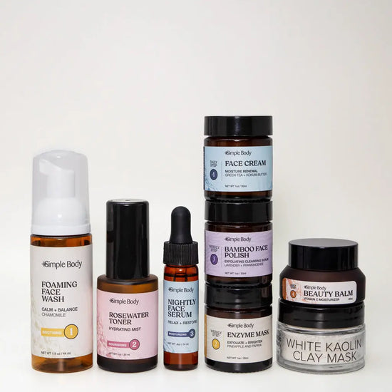 A Mini Starter Skincare kit for sensitive skin including a Foaming Face Wash, Rosewater Toner, Nightly Face Serum, Face Cream, Bamboo Face Polish, Enzyme Mask, Beauty Balm, and Clay Mask on a light tan background.