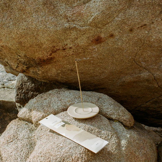 Small stone dish with a stick of Juniper Ridge Campfire Incense in Desert Pinon on a large rock