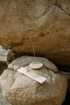 Small stone dish with a stick of Juniper Ridge Campfire Incense in Desert Pinon on a large rock