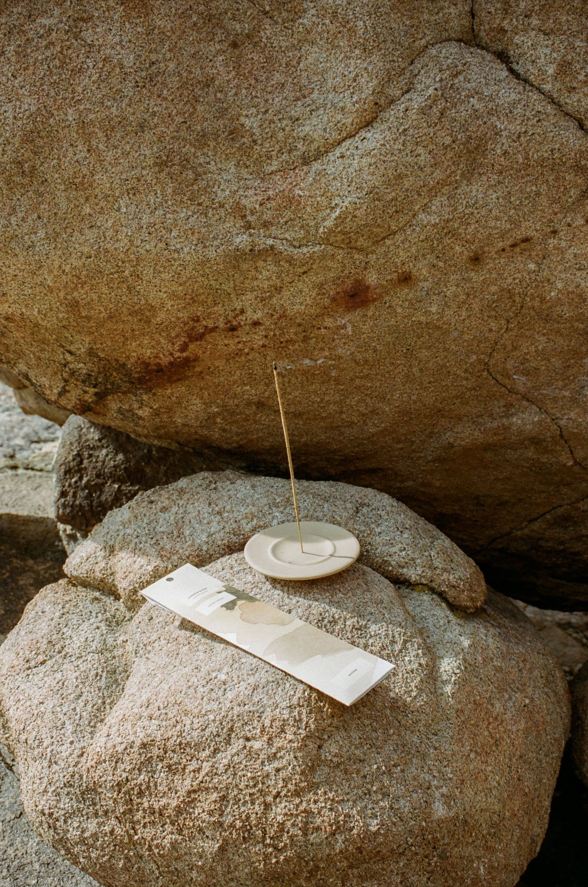 Small stone dish with a stick of Juniper Ridge Campfire Incense in Desert Pinon on a large rock