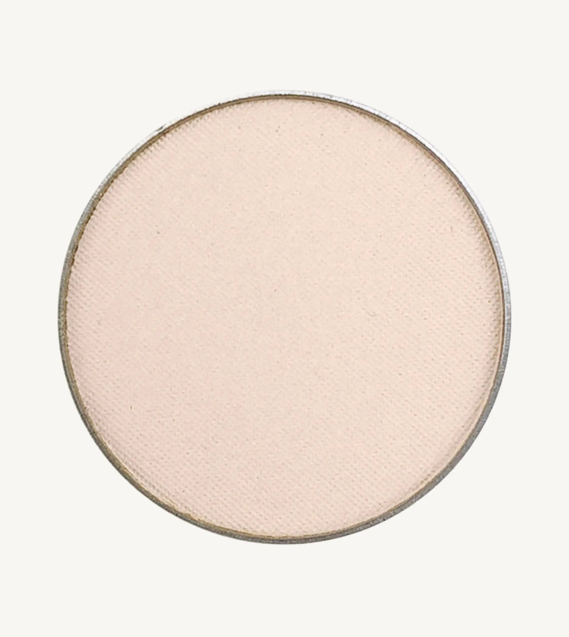 A photo of Pure Anada's Pressed Eye Color in Ivory Tower which is an off-white color with a pinkish hue on a tan background.