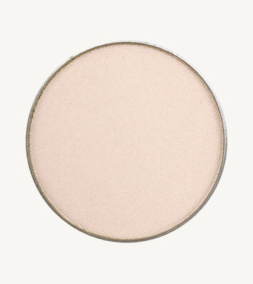 A photo of Pure Anada's Pressed Eye Color in Ivory Tower which is an off-white color with a pinkish hue on a tan background.