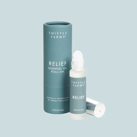 Thistle Farms Relief essential oil roll-on bottle and packaging on a light blue background