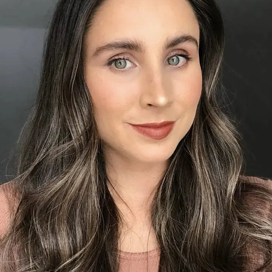 Woman with long, wavy hair against a neutral background wearing warm orange brown lip liner by Pure Anada.