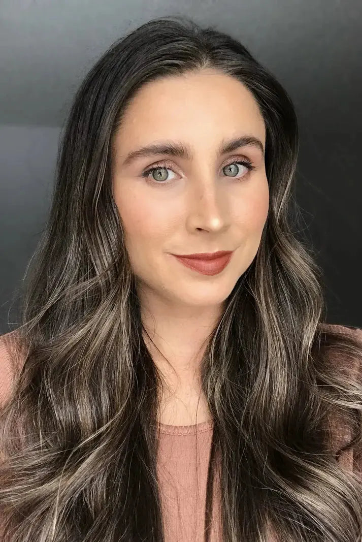 Woman with long, wavy hair against a neutral background wearing warm orange brown lip liner by Pure Anada.