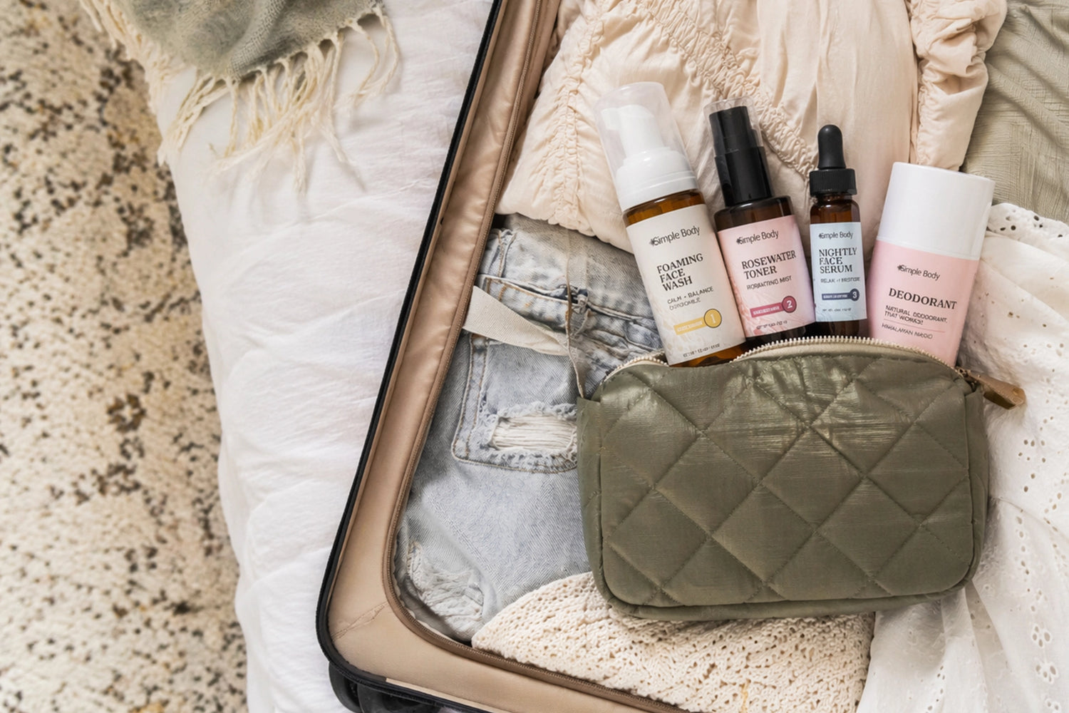 Simple Body Foaming Face Wash, Rosewater Toner, Nightly Face Serum and Deodorant in a green travel bag lying down in a suitcase ready for adventure.