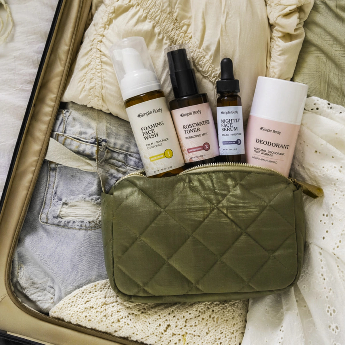 Simple Body Foaming Face Wash, Rosewater Toner, Nightly Face Serum and Deodorant in a green travel bag lying down in a suitcase ready for adventure.