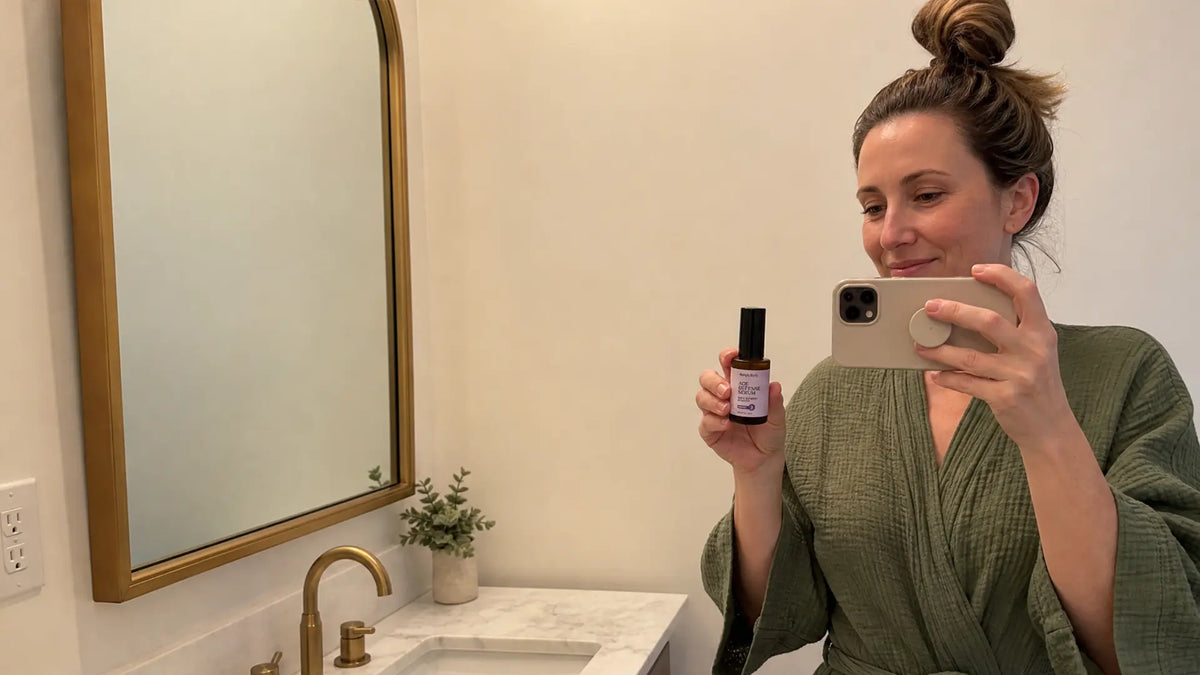 A Woman takes a selfie in a bathroom with Simple Body Age Defense Serum. AI