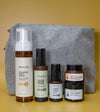 A Starter Skincare Kit for combination skin with a foaming face wash, Clean Sweep Toner, Nightly Face Serum, Beauty Balm, Face Cream, and a gray cosmetic bag on a yellow background.