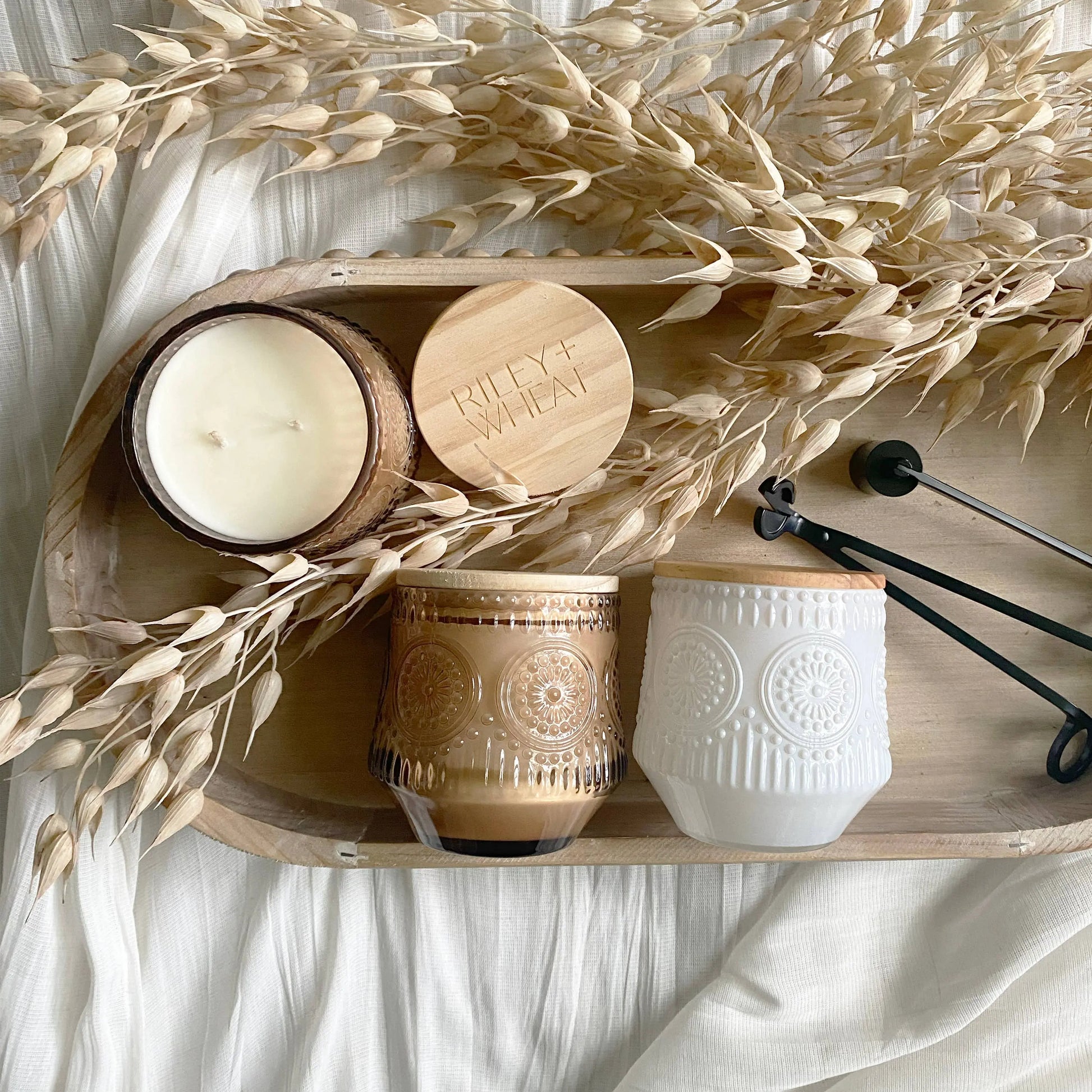 Decorative tray with candles and a wooden block on a white fabric background
