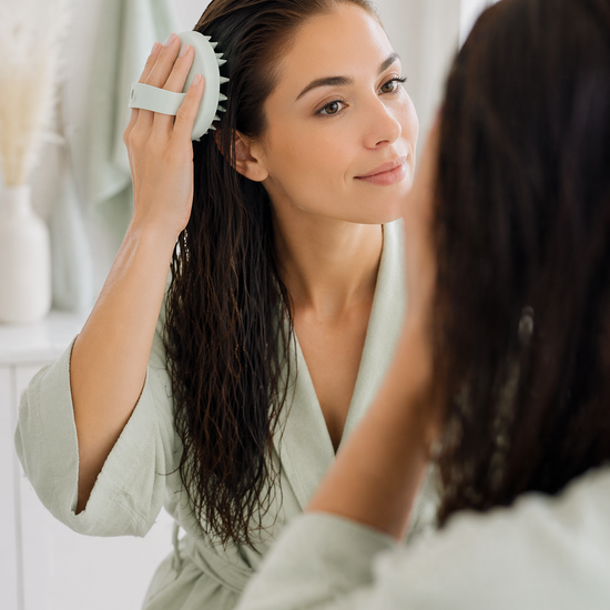 An image of a woman using a mint green hair and scalp brush on wet hair. Image generated via AI.