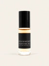 A small glass bottle of Woodberry Perfume Oil from Benjamin Soap Co with a black cap and black label, containing a warm amber liquid, centered on a light cream background.
