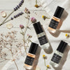 Four bottles of Lavender Soap Co. perfume oil on a light wooden surface with flowers.