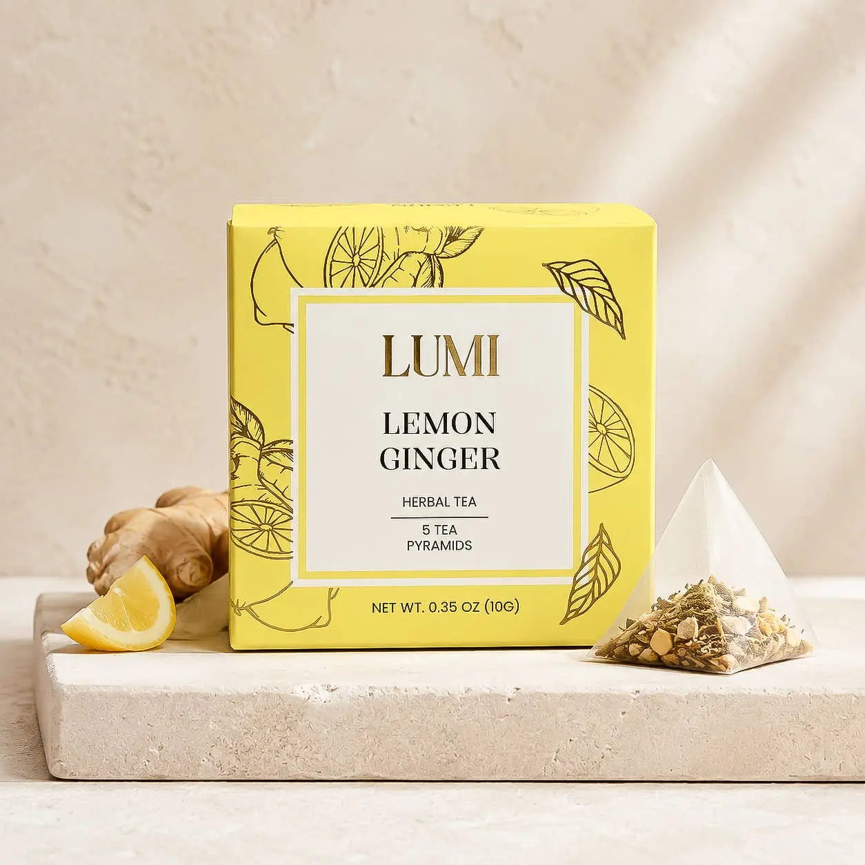 A box of LUMI Lemon Ginger herbal tea sits on a light stone surface with a lemon wedge, ginger root, and a pyramid tea bag beside it. The box is bright yellow with black botanical line art and a white front label.
