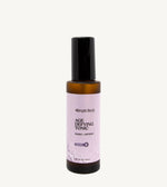 An amber bottle of Simple Body Age Defying Tonic on a tan background